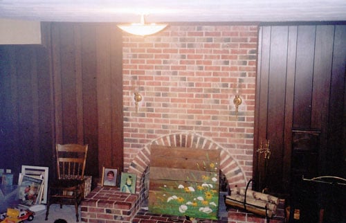 A Family Room With A Brick Fireplace And Blue Curtains