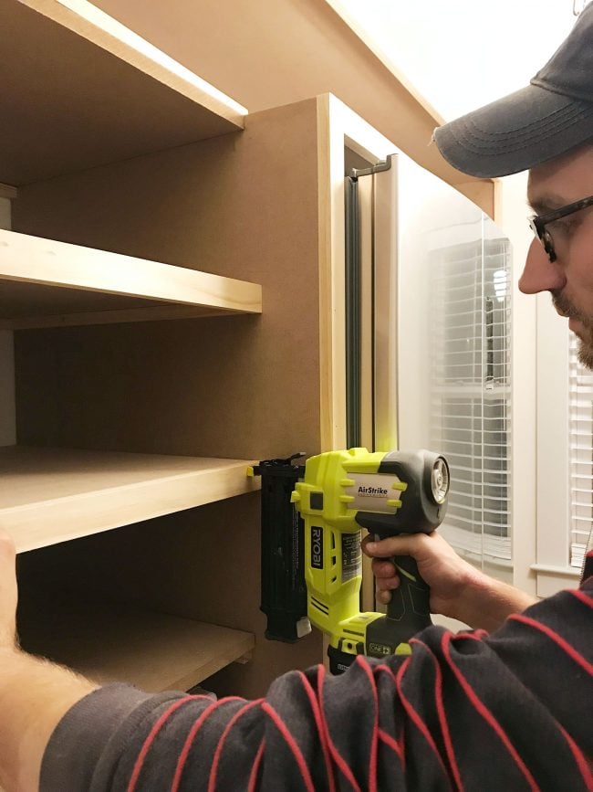 John nailing face pieces onto pantry shelves