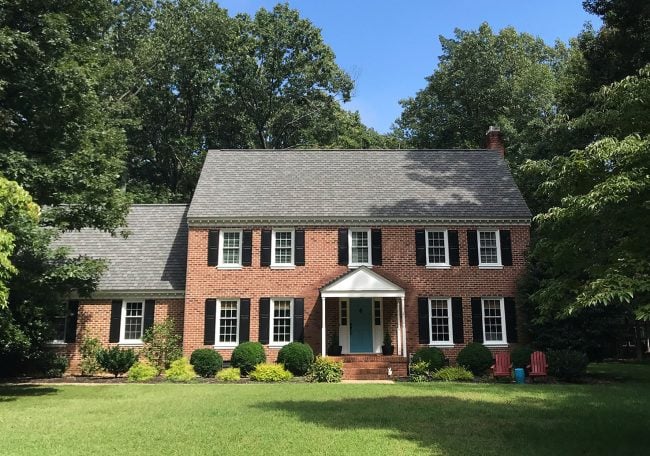 before photo of brick house with black shutters to be painted white