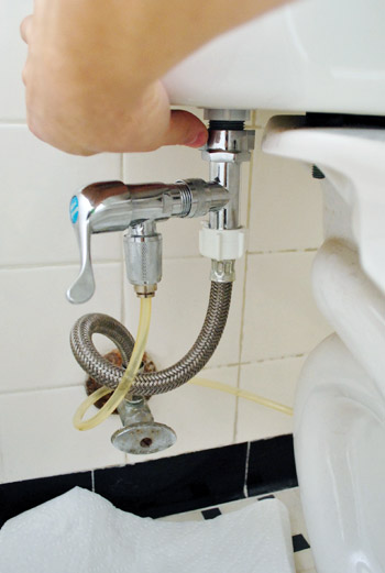 Detaching water supply line from the underside of toilet tank