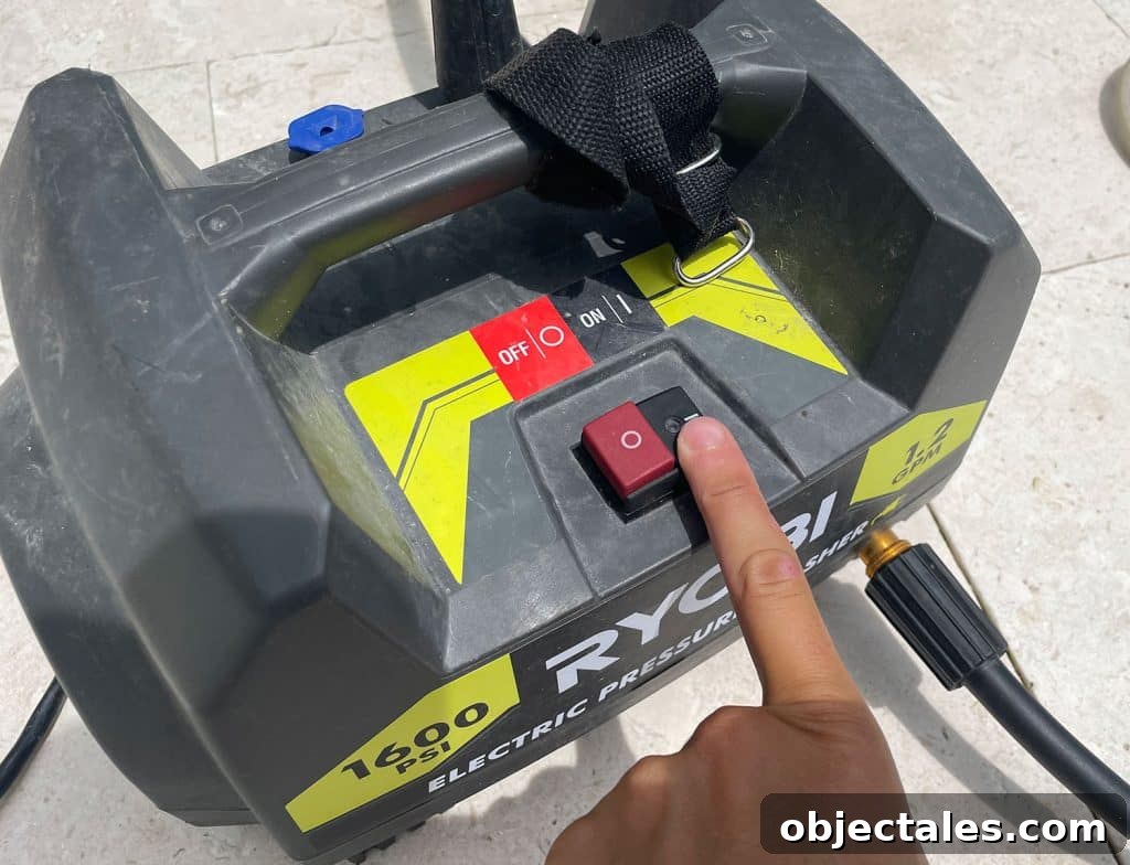 Pressing power button on Ryobi electric pressure washer