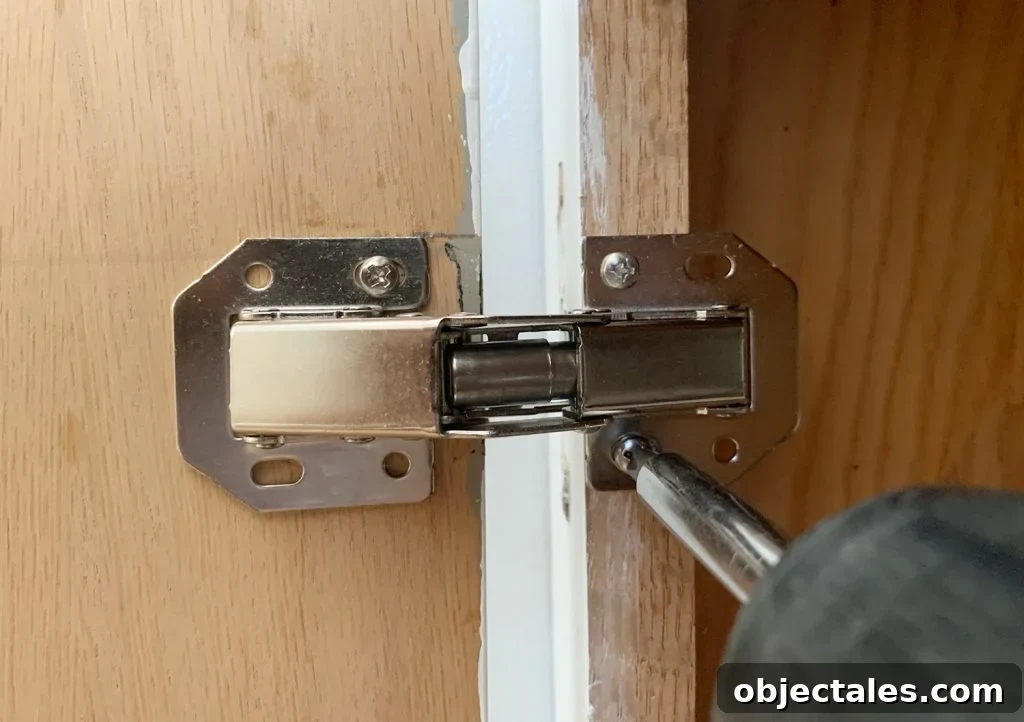 Screwing hidden hinge onto cabinet frame in kitchen renovation