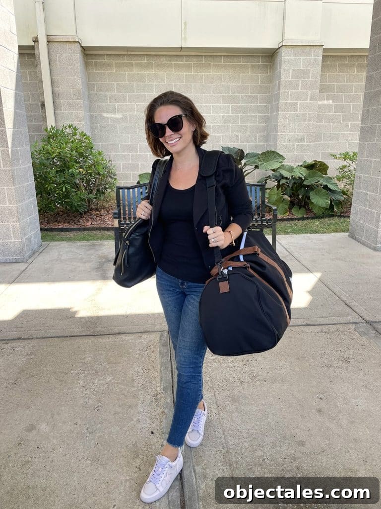 Sherry with purse and duffel bag at airport with black jacket and black tank top and jeans