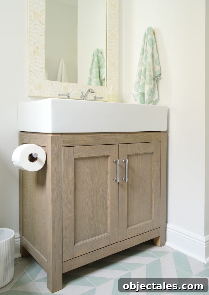 Wood vanity in modern bathroom with mint chevron tile floor