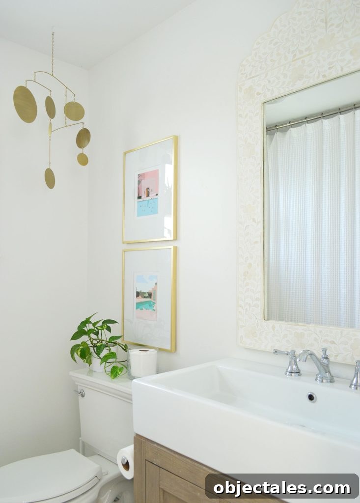 White bathroom with inlay mirror gold picture frames and brass mobile