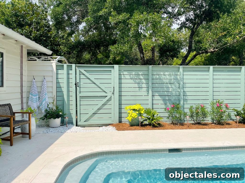 Green fence connected to outdoor shower next to backyard pool