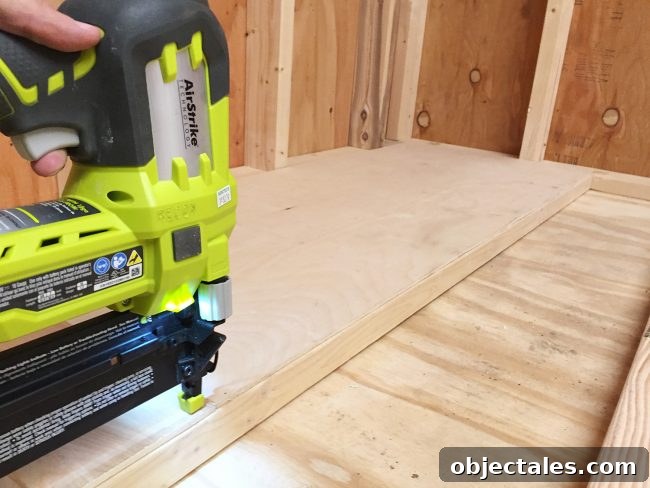 nailing plywood panel onto the bottom level of scrap wood storage organizer