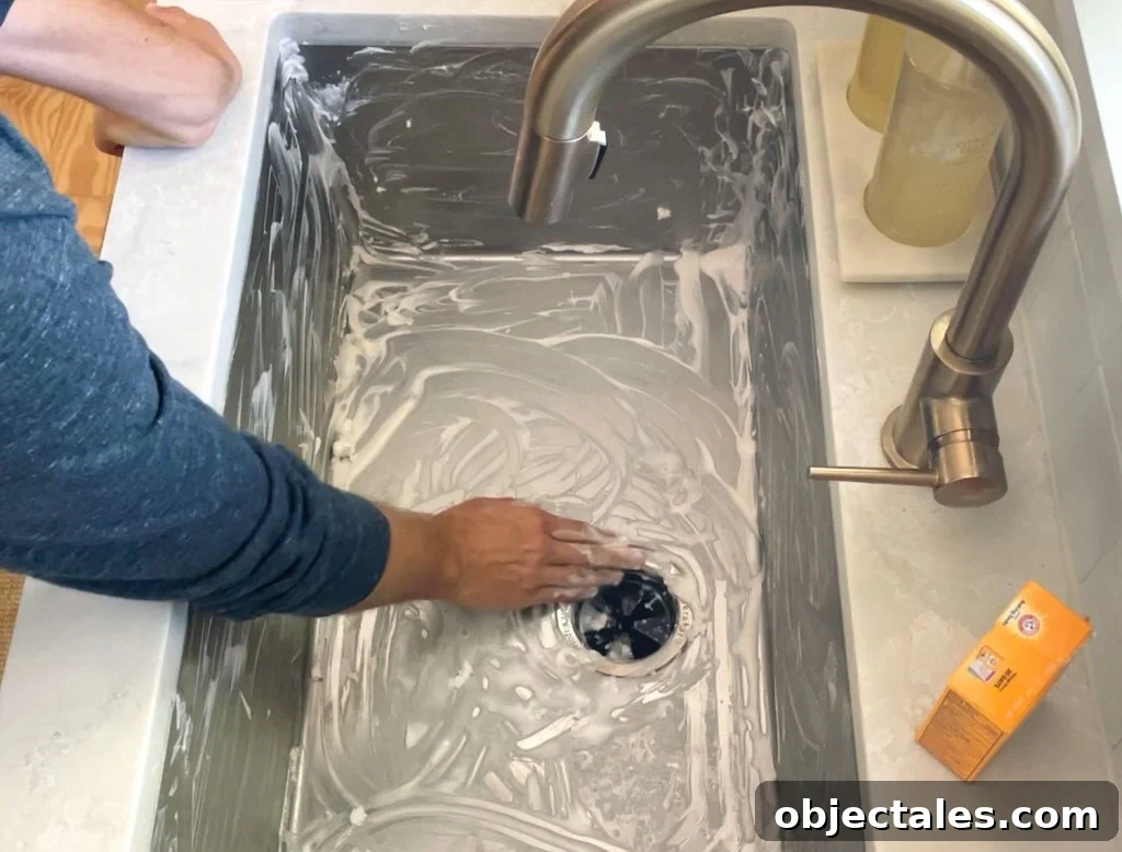 Hand scrubbing a stainless steel sink clean with baking soda