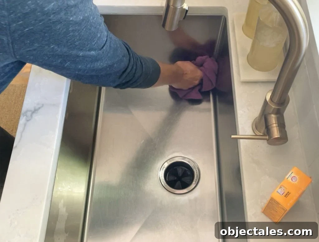 Buffing cleaned stainless steel sink dry with rag