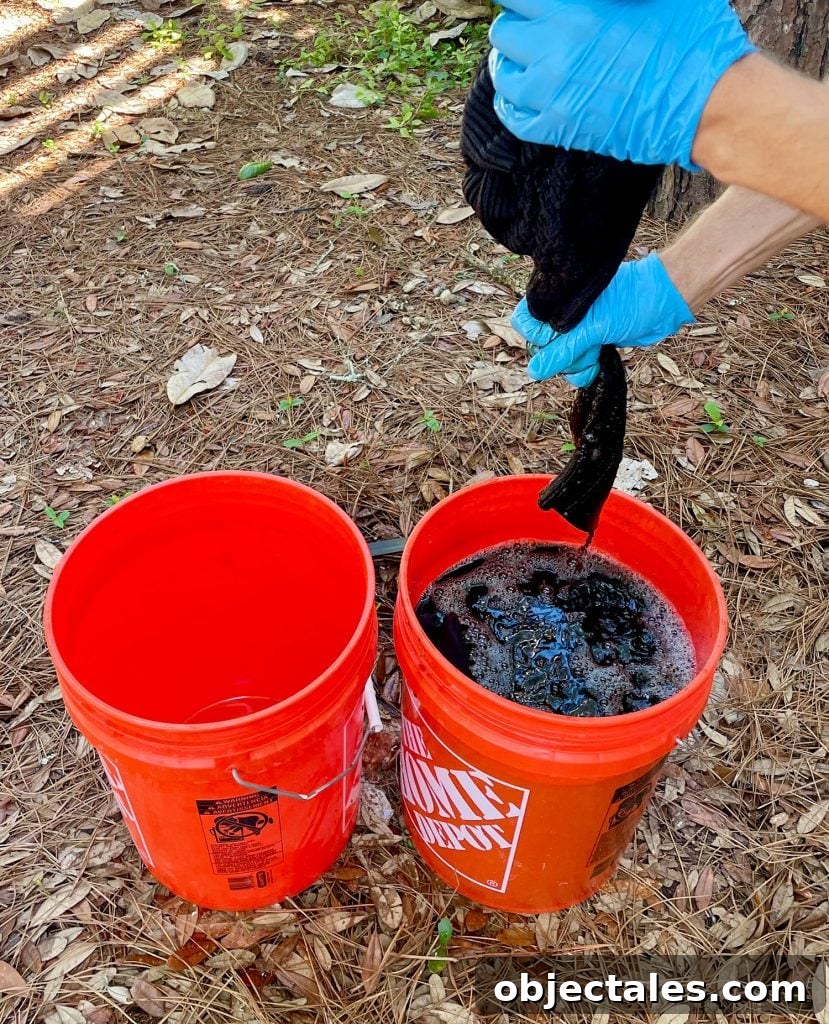 How to Dye Clothes at Home: Step-by-Step Tutorial 12 Squeezing Out Excess Fabric Dye From Black Sweater Over Bucket