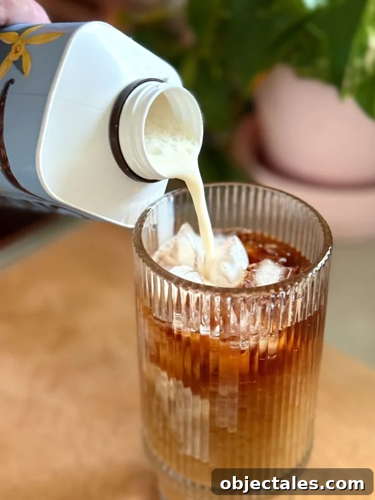 Pouring Creamer Into Glass of Iced Cold Brew Coffee Made At Home