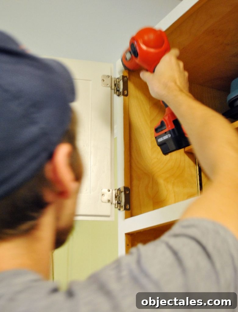 John reattaching cabinet door in painted kitchen