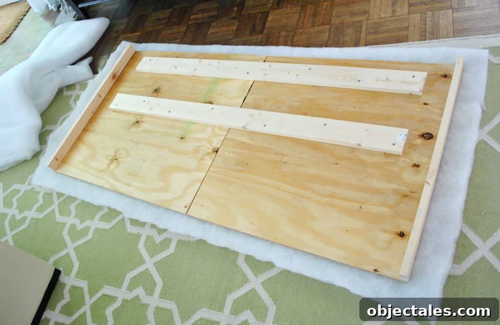 Layer of batting placed under DIY headboard wood frame