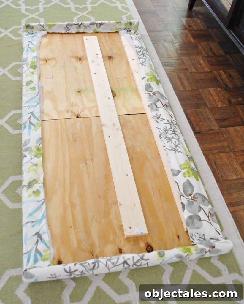 Fabric fully stapled along the backside of wooden headboard frame