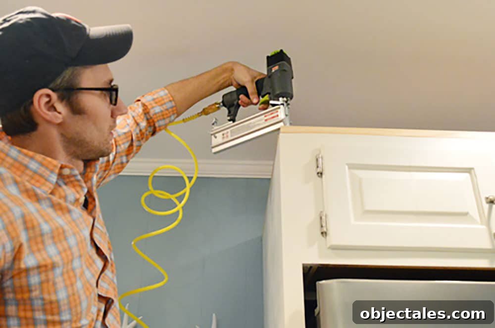 Install Crown Molding on Cabinets: DIY Step by Step Guide 6 John using nail gun to attached scrap wood to top of cabinet