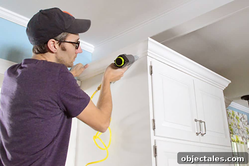 Install Crown Molding on Cabinets: DIY Step by Step Guide 8 John using nail gun to attach crown molding to the top of the cabinets