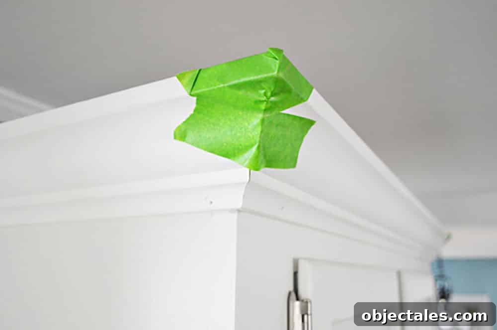 Install Crown Molding on Cabinets: DIY Step by Step Guide 9 Green painters tape on the corner of kitchen crown molding while glue dries
