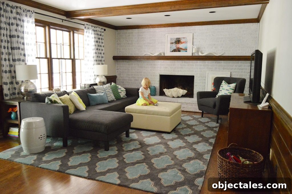 stylish and colorful living room with navy blue furniture, graphic pillows and rug, wood beams, and whitewash brick fireplace wall