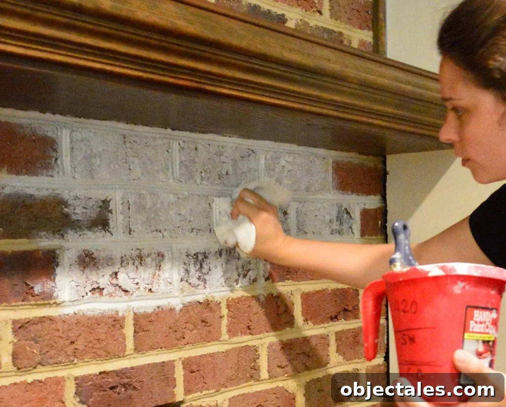 Sherry dabbing watered down white paint on brick wall