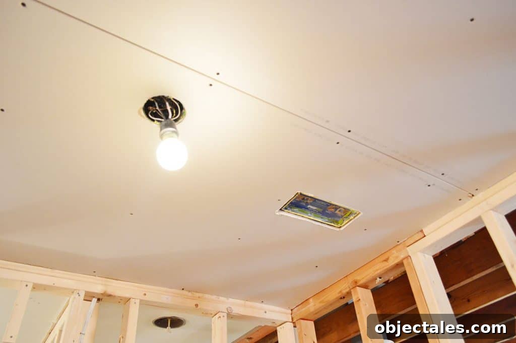 Hang Drywall Alone: Step-by-Step DIY Guide for One Person 9 drywall hung in ceiling with hole cut for light and HVAC vent