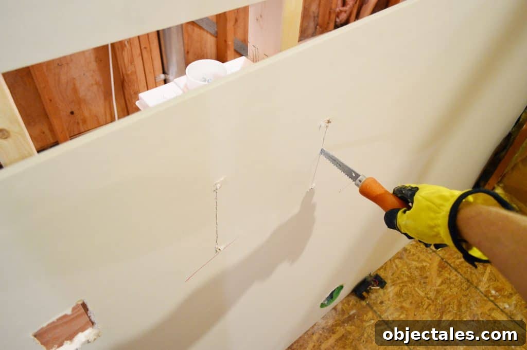 Hang Drywall Alone: Step-by-Step DIY Guide for One Person 6 using drywall saw to cut hole for laundry plumbing in drywall sheet