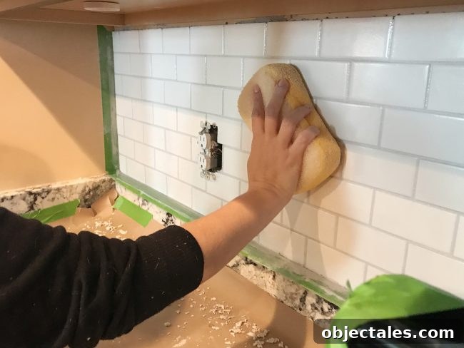 Sherry wiping grout smooth on kitchen backsplash using a damp sponge