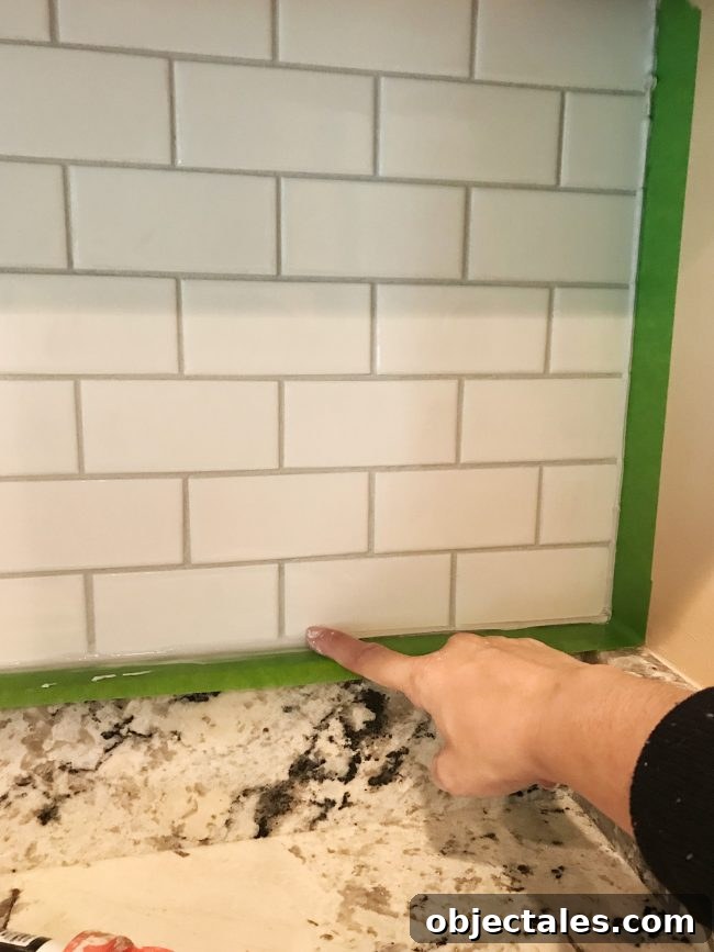 Sherry spreading caulk with finger along edges of installed backsplash