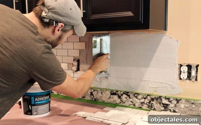 John scraping mastic with v-notch trowel on backsplash wall