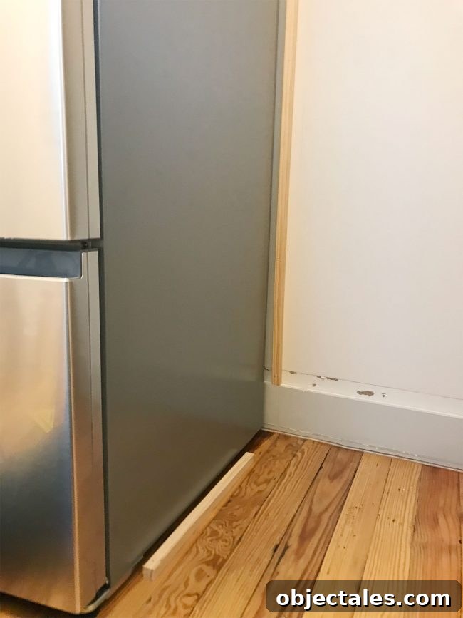 thing pieces of wood installed near fridge on wall and floor