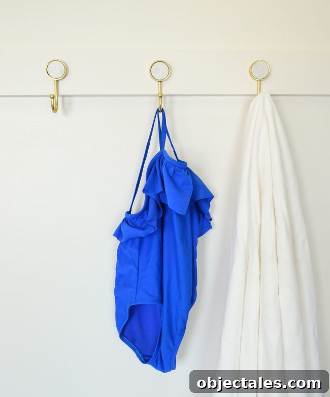 Build a Long Hook Rail for Your Mudroom 8 three gold hooks on diy rail with towel and bathing suit