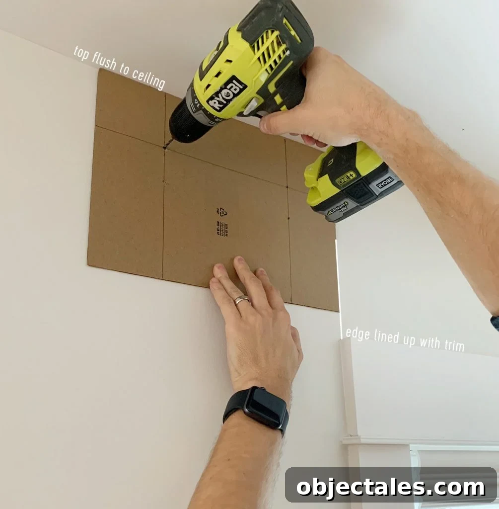 Drilling through curtain rod hanging template to create pilot holes