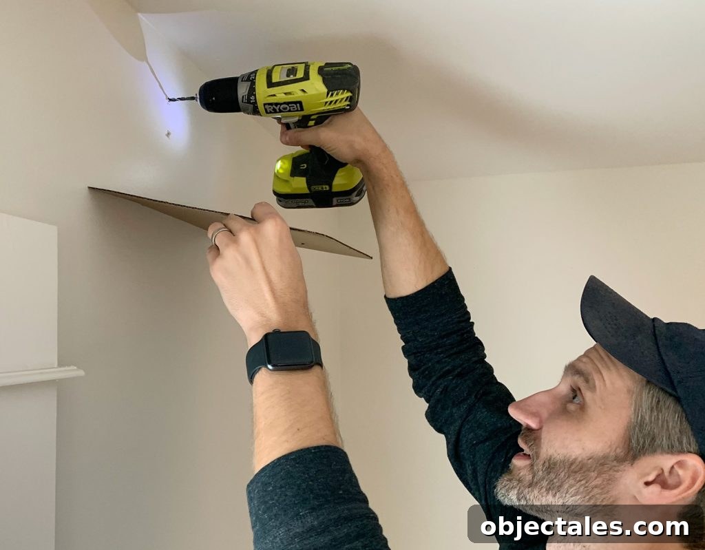 Drilling larger holes for curtain rod using cardboard to catch dust