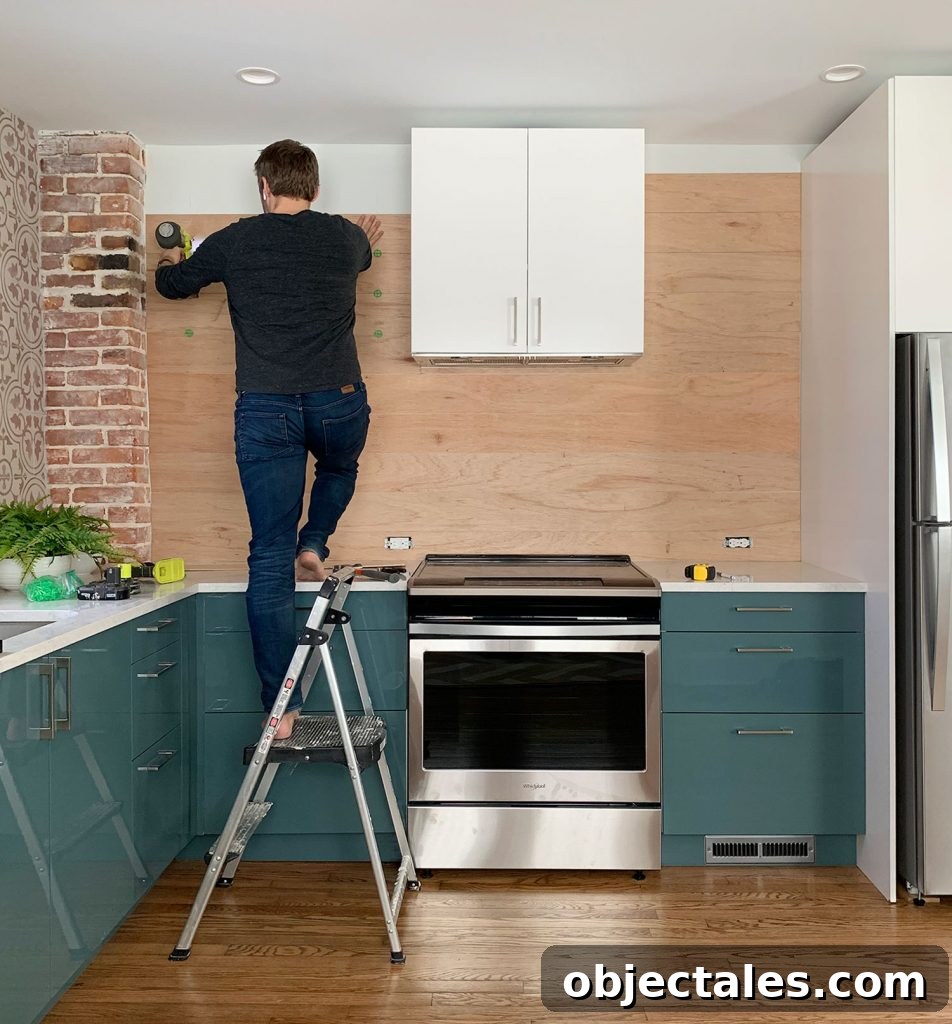 Shiplap Wall Plank Makeover for Just 31 Dollars 20 John Standing On Ladder Nailing Wood Paneled Backsplash In Blue Kitchen