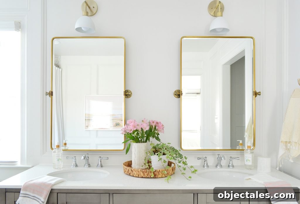 Two gold pivot mirrors over gray bathroom double vanity
