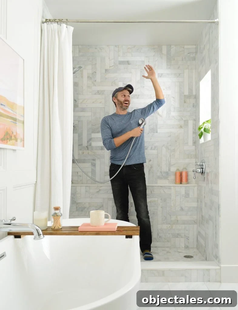 John standing in marble tiled shower pretending to shower
