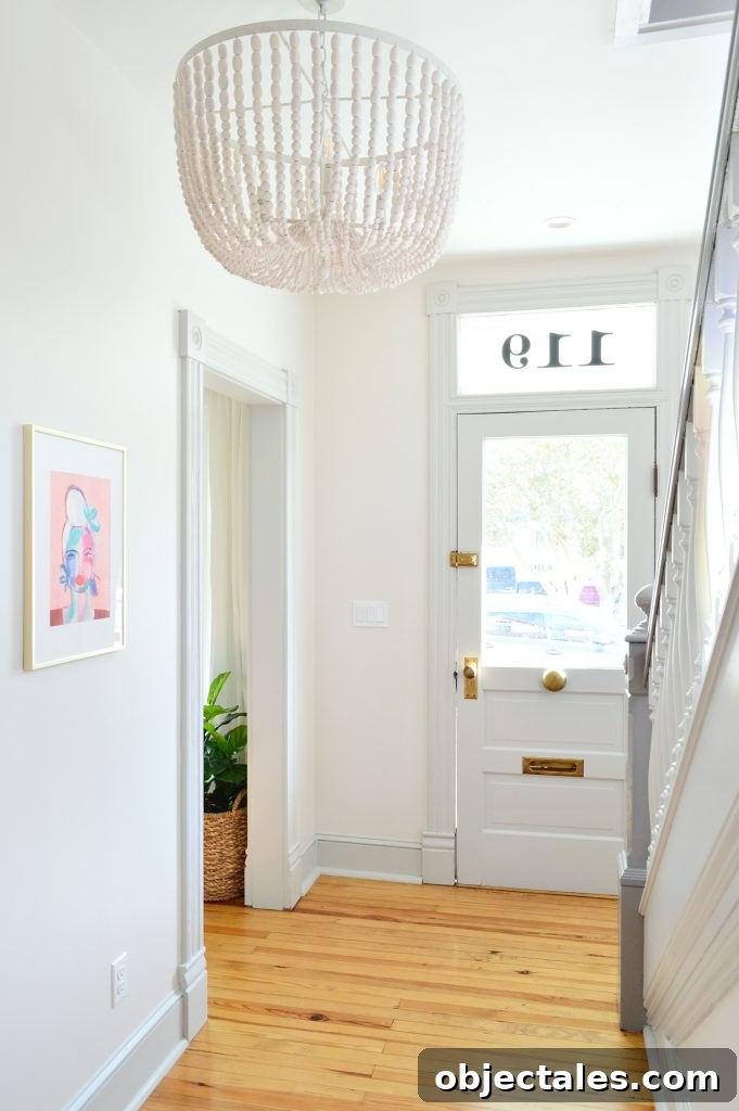 7 Beach House Updates: What We Changed and Why 5 Beaded Chandelier In Beach House Foyer With Glass Front Door And Pink Art