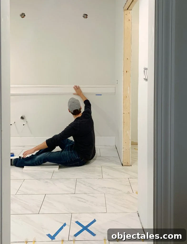 John Holding Test Piece Of Wall Molding In Bathroom
