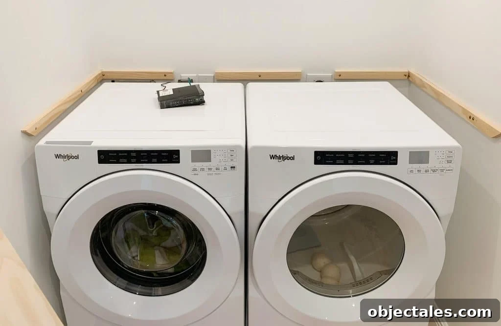 Wood laundry shelf supports added to walls besides washer and dryer