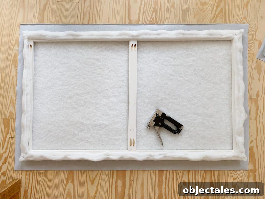 Batting covered wood frame laid on floor atop fabric prior to stapling