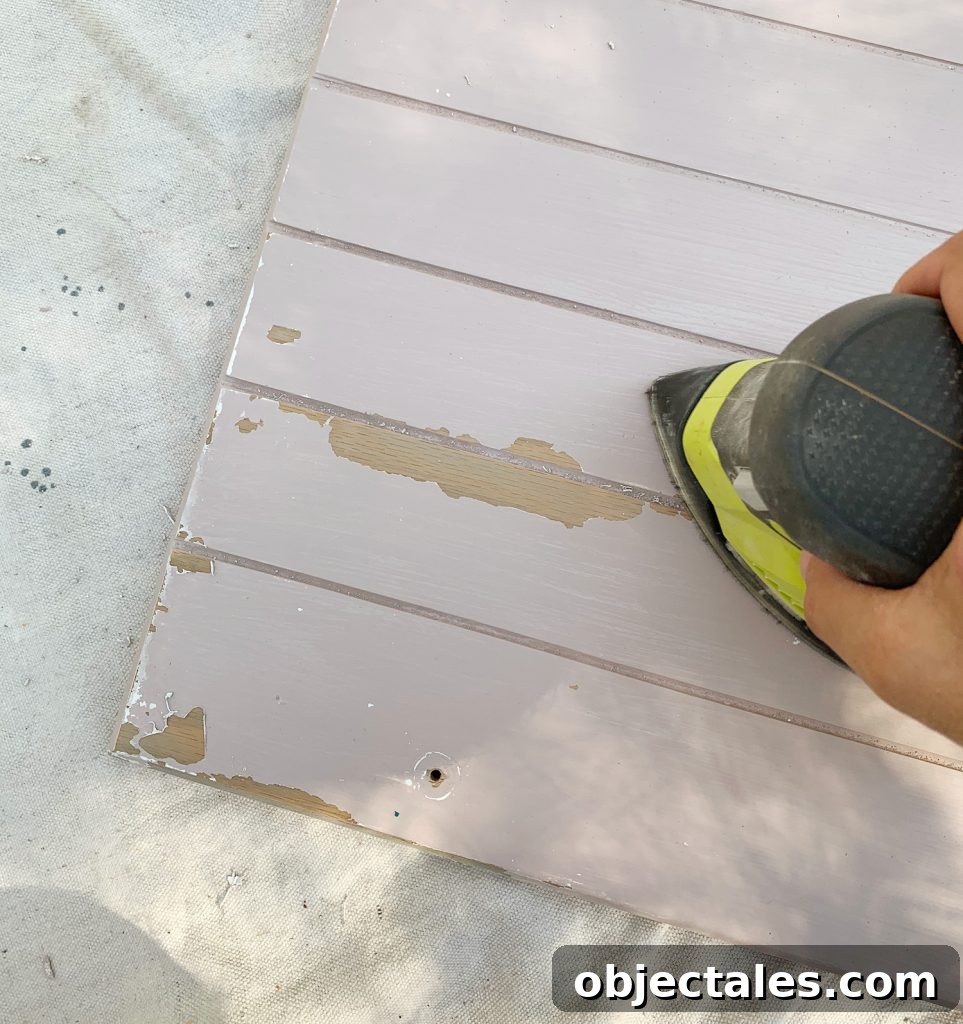 Before and After: Pink Kitchen Cabinets Makeover 12 Sanding old paint drips off of wood cabinets in preparation for cabinet painting