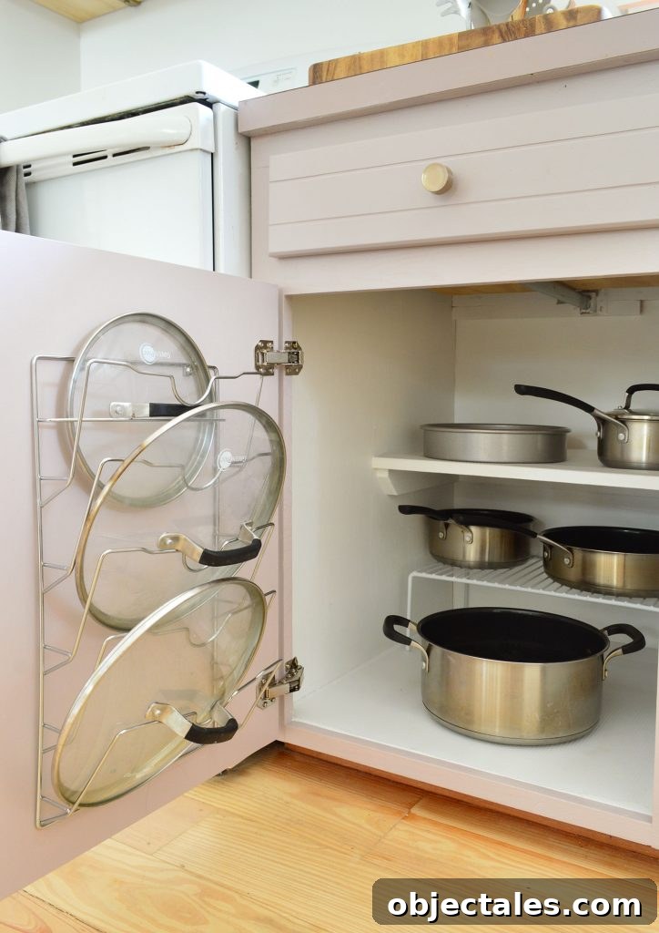Pots and pans organized in small kitchen with lid mounted on cabinet door