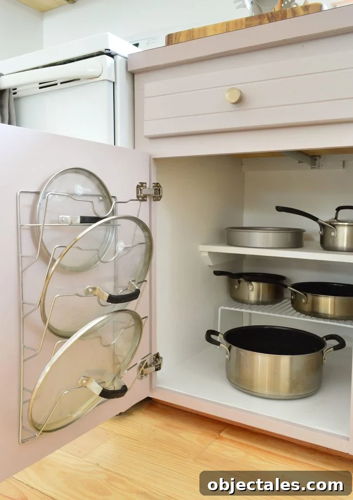 Pots and pans organized in small kitchen with lid mounted on cabinet door