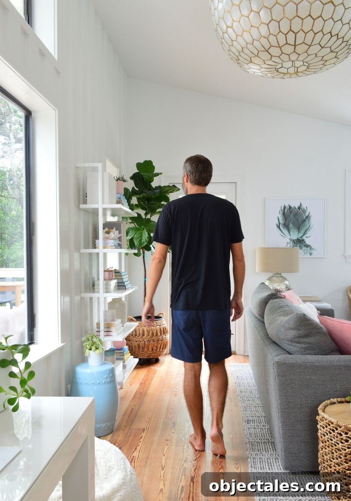 Man In Black Shirt Walking In Living Room Under Large Light Fixture