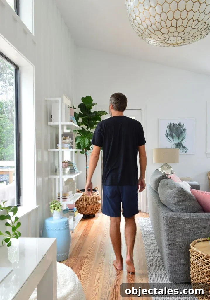 Man In Black Shirt Walking In Living Room Under Large Light Fixture