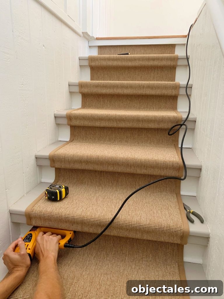 Hand Pushing Electric Stapler Into Underside Of Stair Tread To Secure Sisal Runner
