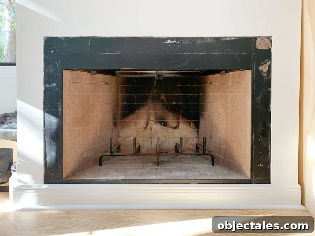 Before photo of fireplace with charred brick interior and patchy black metal surround
