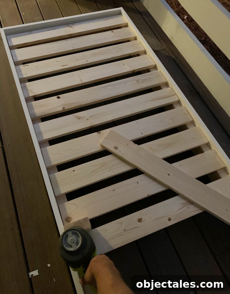 Build a Hanging Daybed: Step-by-Step DIY Tutorial 12 Nailing 1x4 slat across top of platform frame