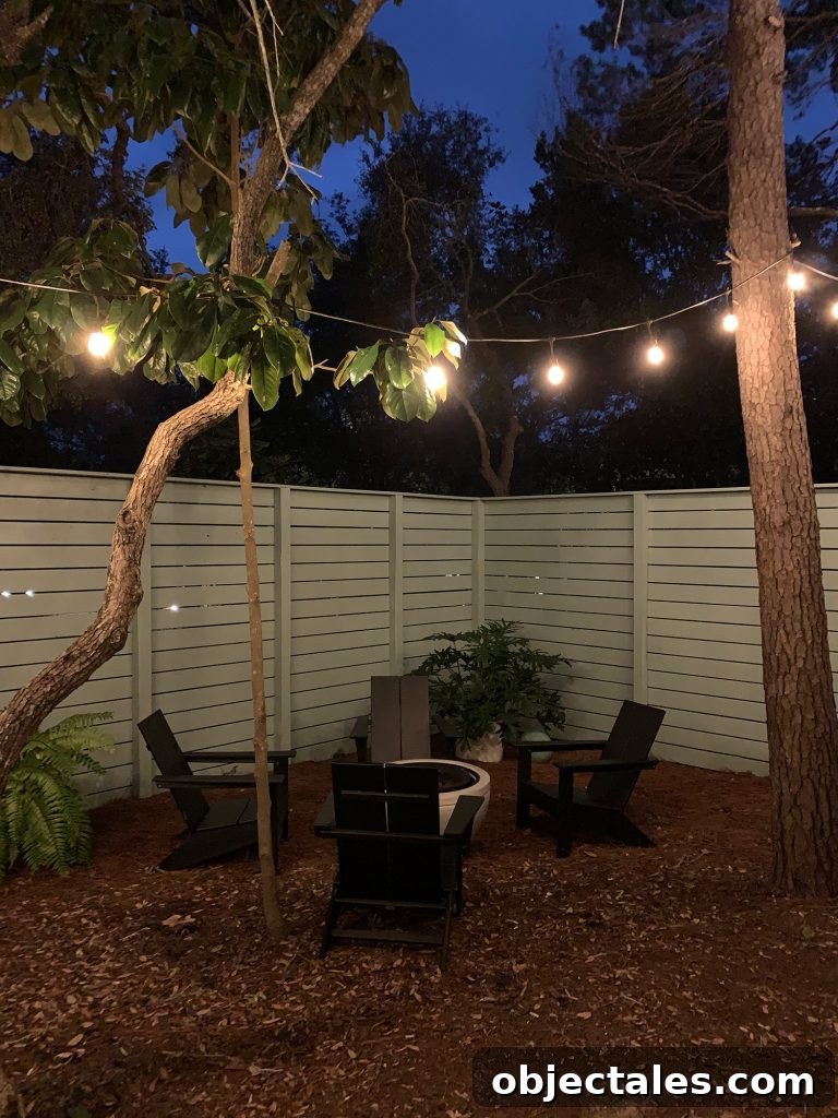 Create a Cozy Fire Pit Area for Outdoor Gatherings 4 Nighttime view of fenced side yard with black Adirondack chairs around fire pit