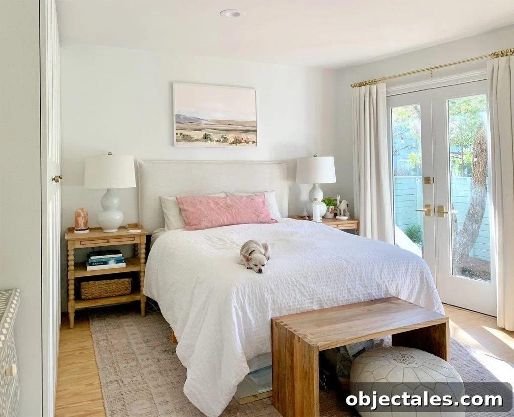 Bedroom with pink rug with french doors next to white bed
