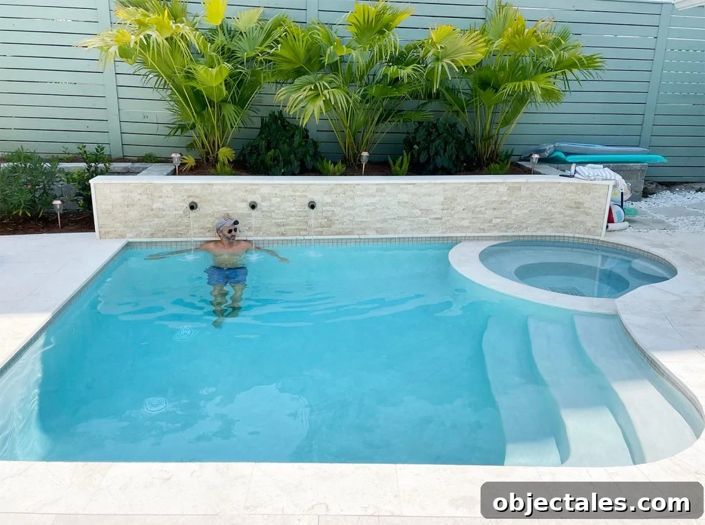 John in small freeform pool against stone accent retaining wall under palm plants